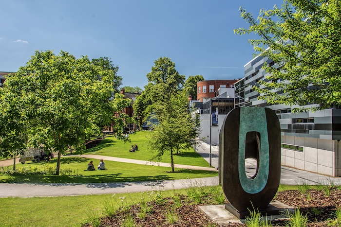 Dual Form sculpture by Barbara Hepworth with people relaxing on grass in background